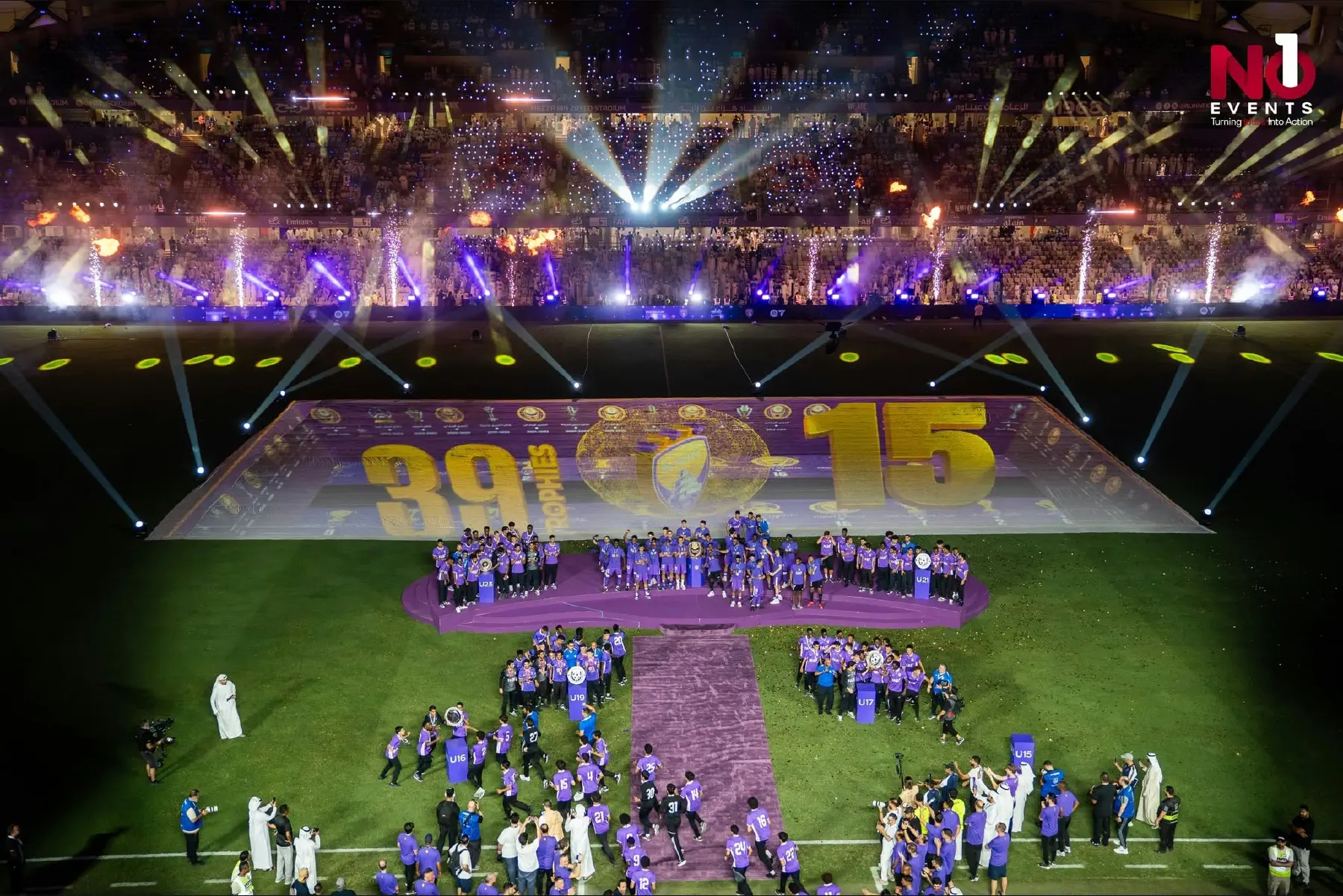 Purple beams across the bowl of Hazza bin Zayed Stadium with a gold 39/15 title graphic projected onto the pitch