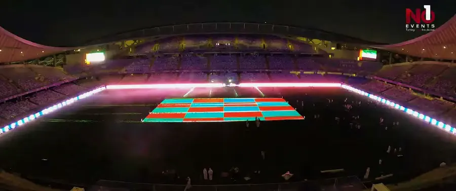 The darkened stadium bowl with magenta perimeter lighting and an LED grid lit across the pitch