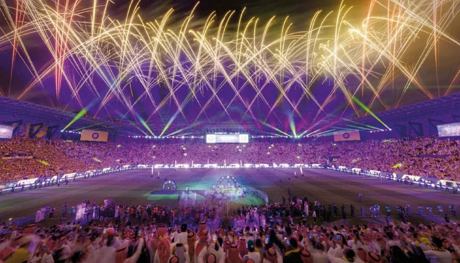 Gold pyrotechnics arcing across the stadium above a crowd in Al Nassr yellow
